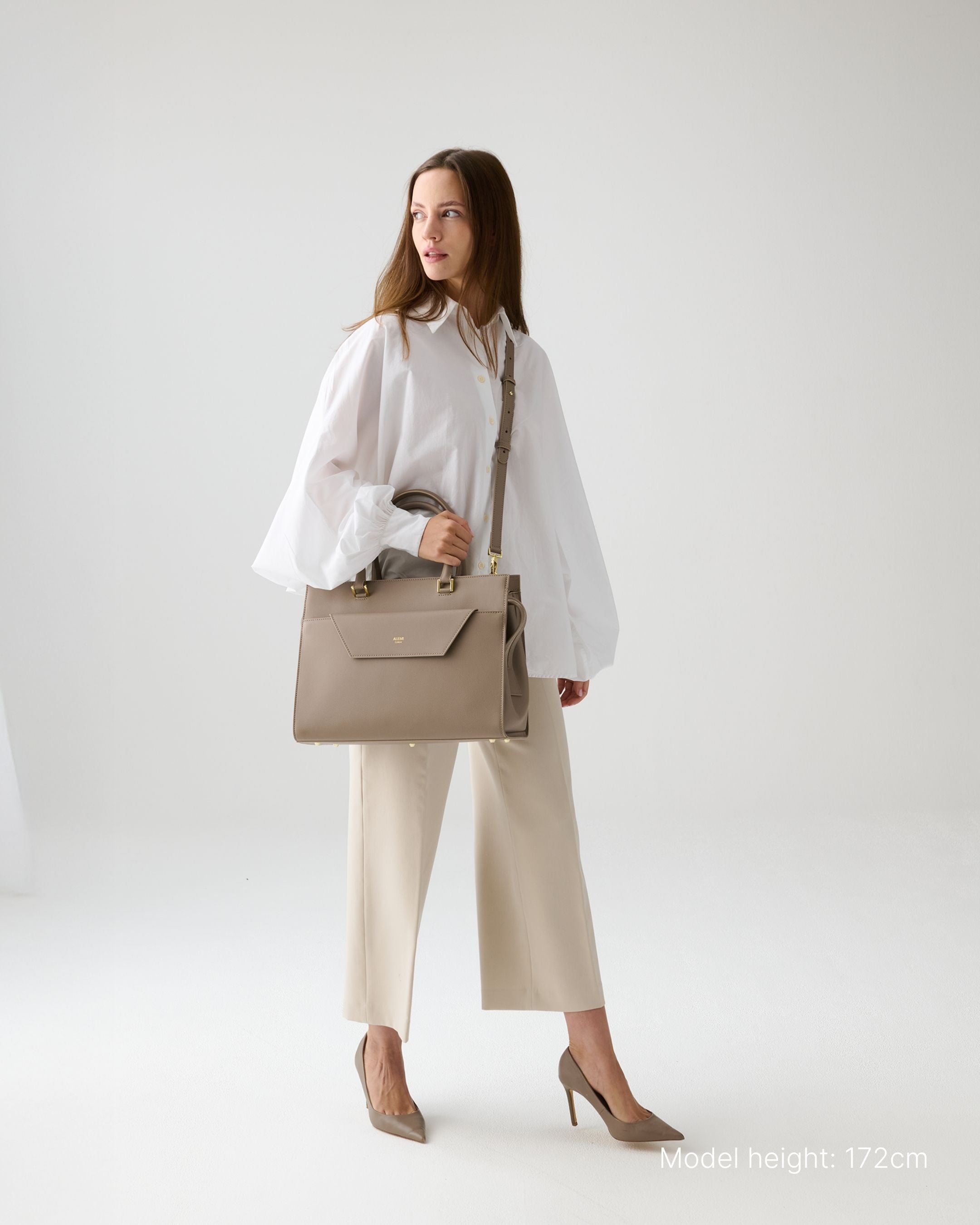 ALEMI Zurich | CENTRAL | Laptop Bag | Greige | Pebbled Leather | Model carrying bag by strap