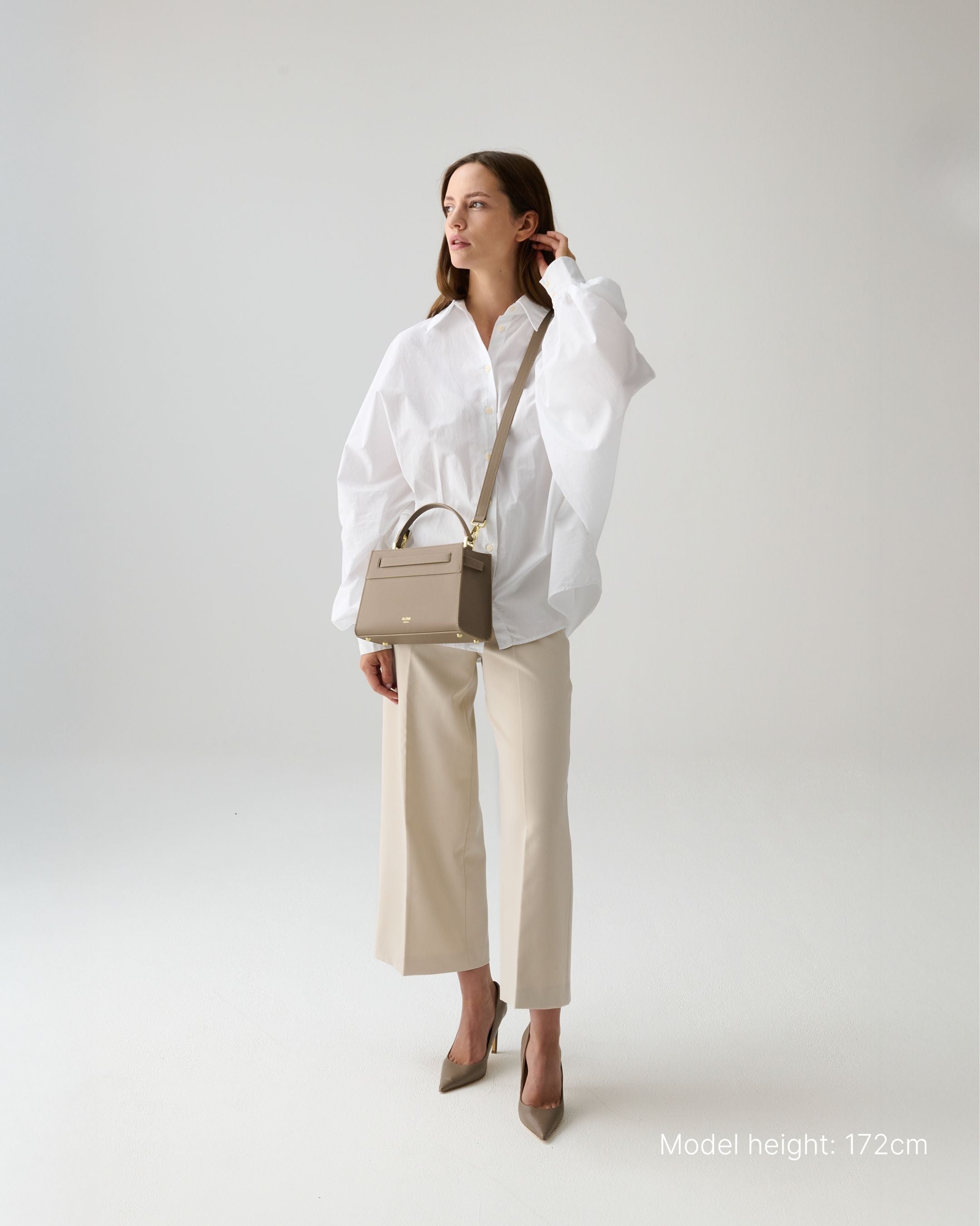 ALEMI Zurich | SEEFELD MINI | Small Bag | Greige | Pebbled Leather | Model carrying bag by strap