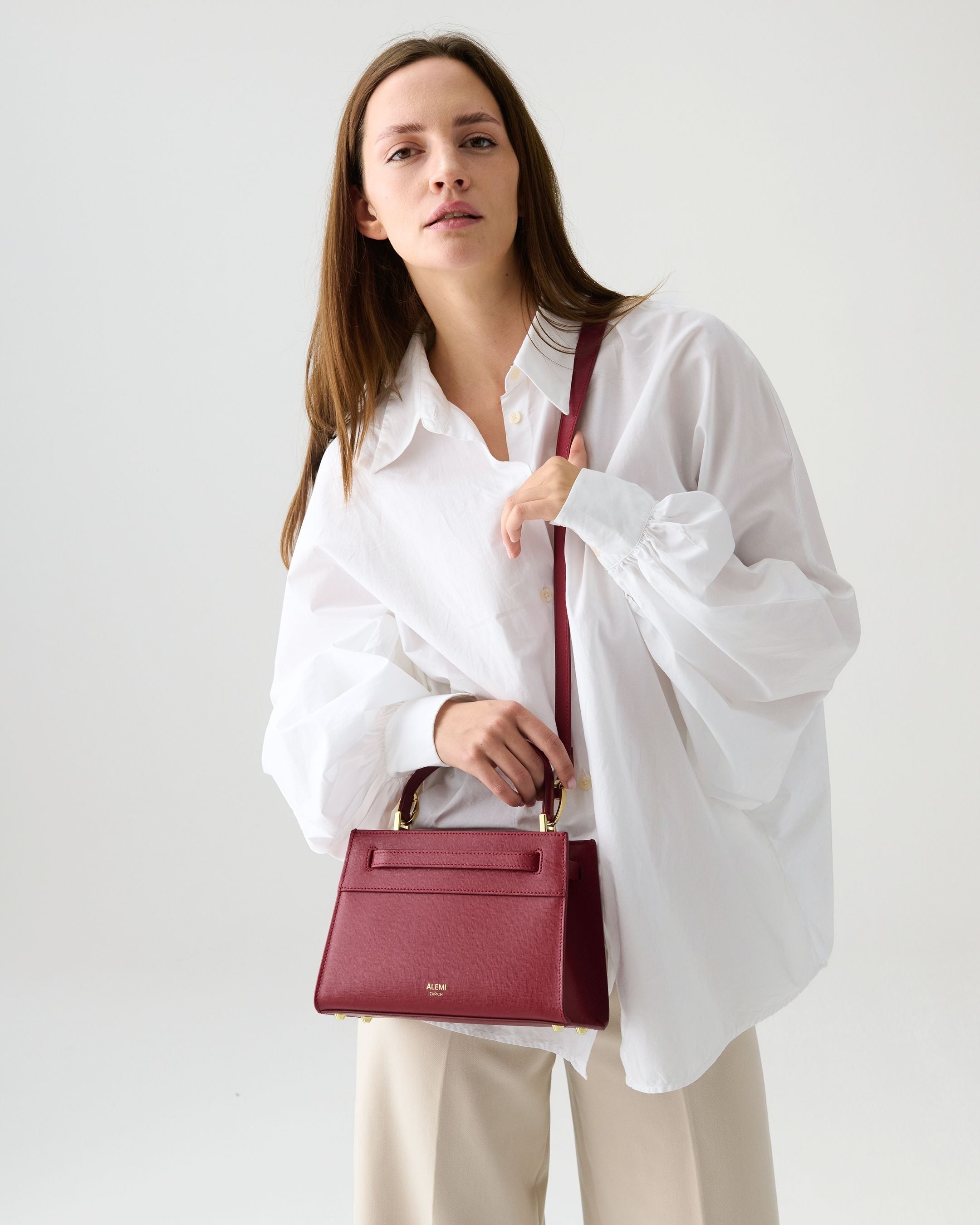 ALEMI Zurich | SEEFELD MINI | Small Bag | Red | Saffiano Leather | Model carrying bag by handle